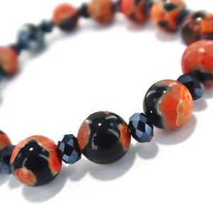 May include: A bracelet made with black and orange agate beads and black crystal beads.