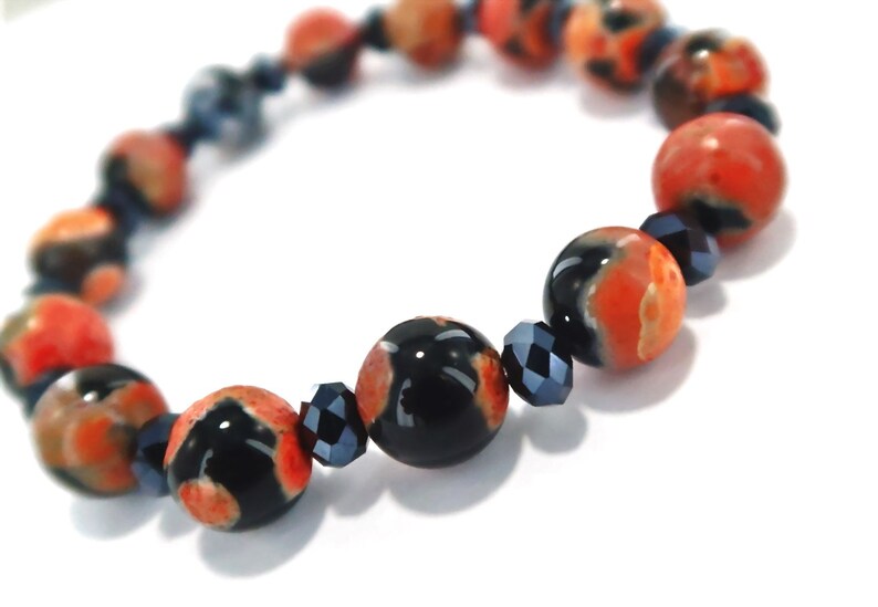 May include: A bracelet made with black and orange agate beads and black crystal beads.