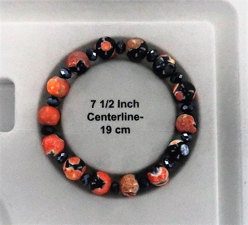 May include: A bracelet made of orange and black beads. The bracelet is 7 1/2 inches in circumference and has a centerline of 19 cm.
