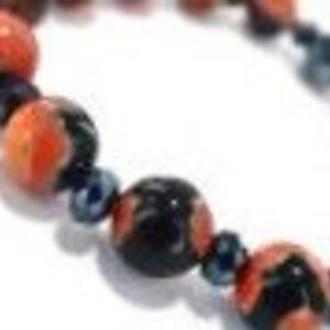 May include: A bracelet made of red, black, and blue beads. The beads are round and have a glossy finish.