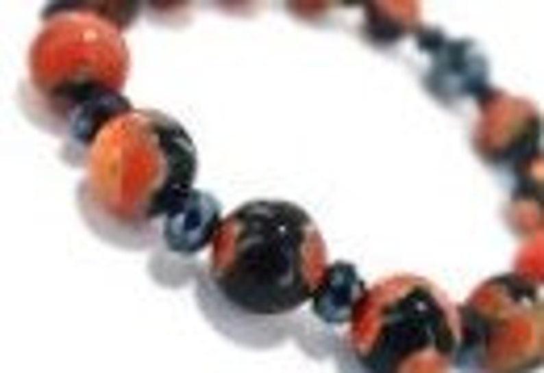 May include: A bracelet made of red, black, and blue beads. The beads are round and have a glossy finish.