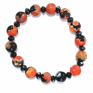 May include: A bracelet made of orange and black agate beads with black crystal accents.