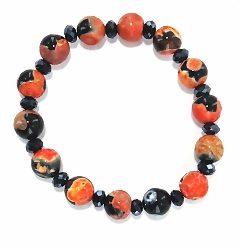May include: A bracelet made of orange and black agate beads with black crystal accents.