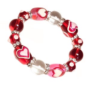 Puede incluir: Una pulsera de cuentas con cuentas rojas, rosas y transparentes alternas. Las cuentas rojas y rosas tienen dise&ntilde;os de corazones blancos. Los espaciadores de diamantes de imitaci&oacute;n plateados a&ntilde;aden brillo.