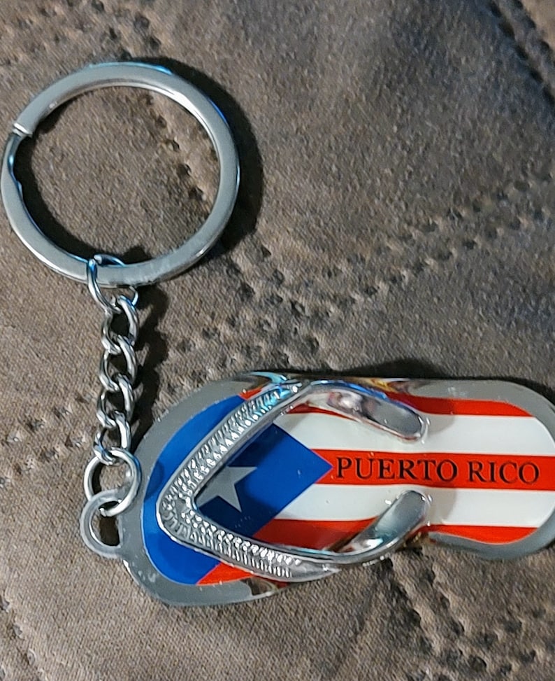 May include: A silver keychain shaped like a flip-flop with the Puerto Rican flag and the text "PUERTO RICO" on it.