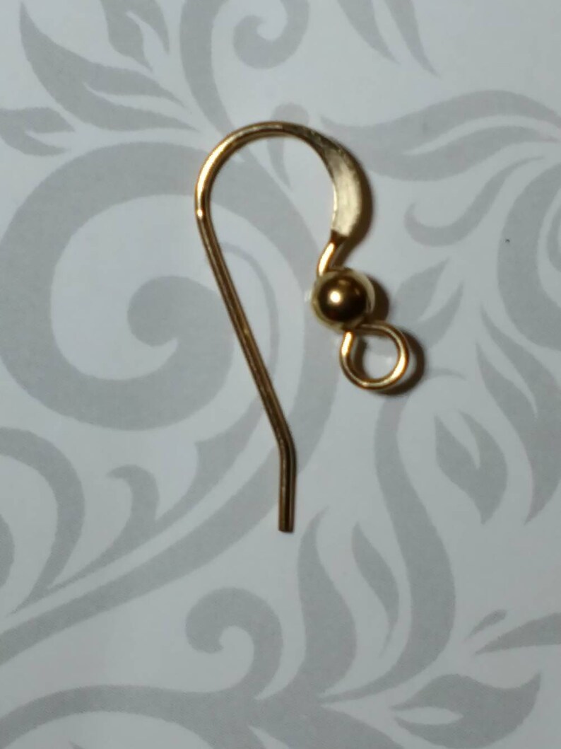 May include: Gold earring hook with a small ball at the top.