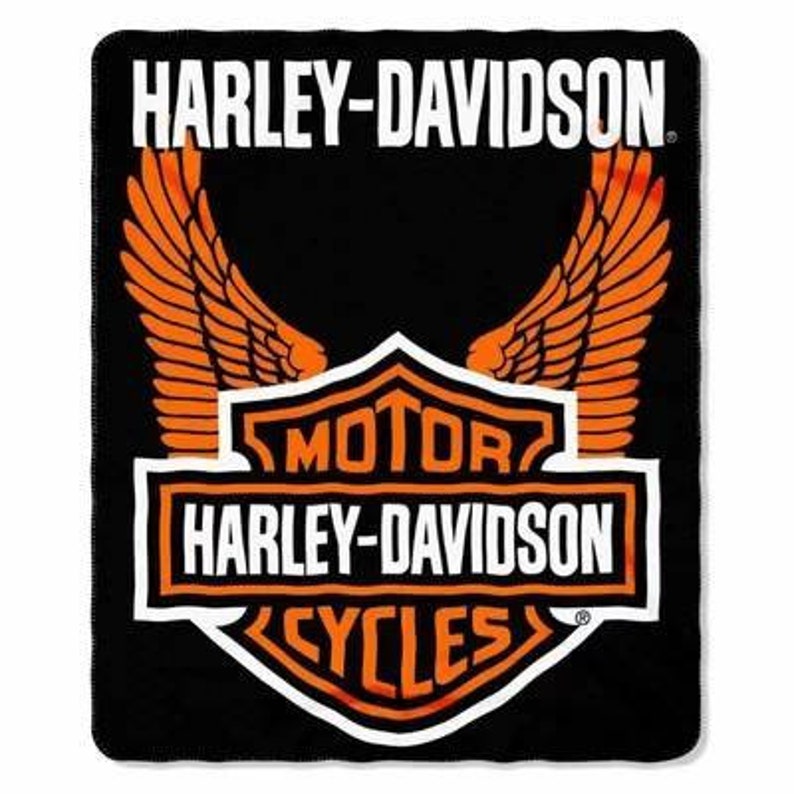 May include: Black blanket featuring the Harley-Davidson logo. The logo includes the words "HARLEY-DAVIDSON" in white, with orange wings and a shield design that reads "MOTOR HARLEY-DAVIDSON CYCLES."