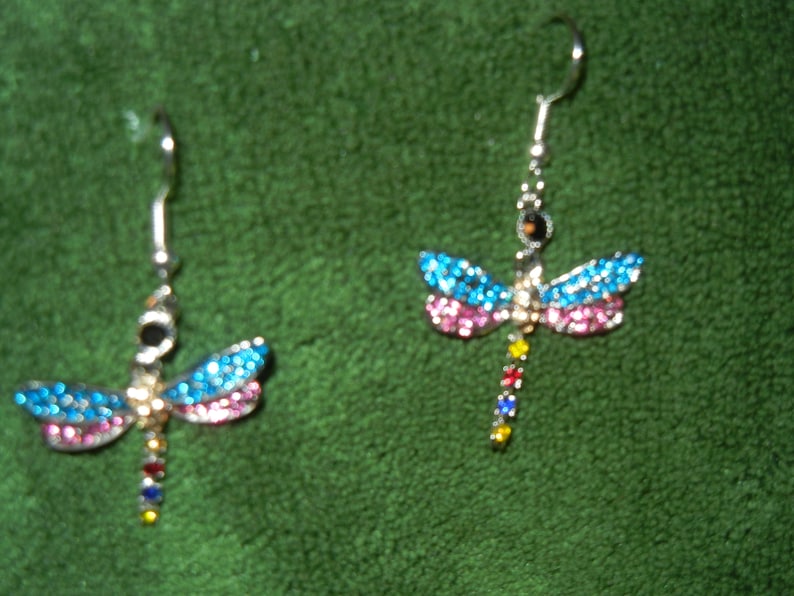 May include: A pair of silver dragonfly earrings with blue, pink, and rainbow colored rhinestones.