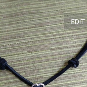 May include: A black leather cord necklace with a silver heart charm.