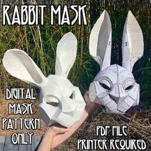 Op de afbeelding: Twee witte konijnenmaskers, één gemonteerd en één in een patroon, worden getoond tegen een achtergrond van groen gebladerte. De tekst "RABBIT MASK" en "DIGITAL MASK PATTERN ONLY" zijn zichtbaar. Het tweede masker heeft de tekst "PDF FILE PRINTER REQUIRED".
