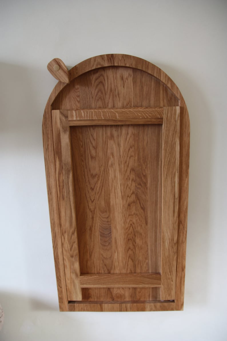 May include: A wooden folding table with an arched top. The table is made of light brown wood and has a simple design.