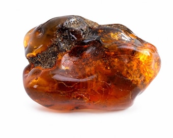 May include: A polished, irregular piece of amber featuring a translucent, deep honey-orange color with visible internal fractures and inclusions. One side displays a dark, textured, and matte brown patch, contrasting with the smooth, glossy surface.