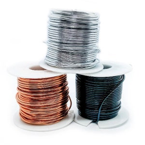 May include: Three spools of wire, one silver, one copper, and one black, are stacked on top of each other.