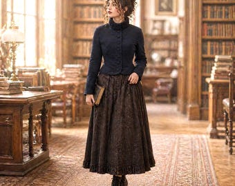 May include: A woman wearing a navy blue jacket with a high collar and a brown floral skirt, holding a book. She is standing in a library with bookshelves and a patterned rug. The jacket has a button-up front.