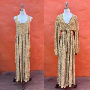 Puede incluir: Dos vestidos con estampado floral sobre maniquíes. Uno es un vestido largo sin mangas con cuello redondo. El otro es un vestido de manga larga con cuello en V y lazo en la cintura. Ambos vestidos tienen un fondo amarillo con pequeños estampados florales.