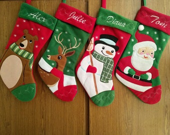May include: Four red and green Christmas stockings with embroidered names "Alex", "Julie", "Diana", and "Tom". Each stocking features a different embroidered character: a bear, a deer, a snowman, and Santa Claus.
