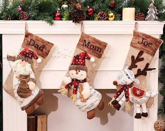 May include: Three personalized Christmas stockings with different characters. The stocking on the left has a Santa Claus character, the middle stocking has a snowman character, and the stocking on the right has a reindeer character. The stockings are labeled "Dad", "Mom", and "Joe".