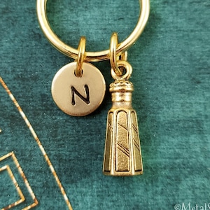 May include: Gold keychain with a small salt shaker charm and a round charm with the letter N.