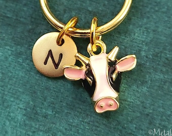 May include: Gold keychain with a black and white cow charm and a gold charm with the letter N.