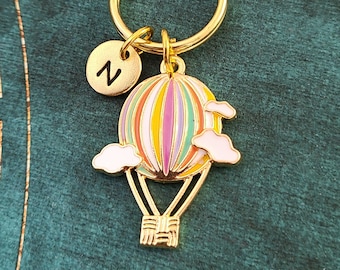 Keychain with the word serene stamped on a washer with hot air balloon charm and green crystal.