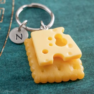 May include: A silver keychain with a letter 'Z' charm and a simulated cheese and cracker snack charm.