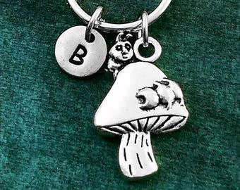 May include: Silver mushroom charm keyring with a letter B charm and a small mushroom charm. The keyring is on a green background.