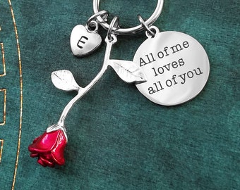 May include: Silver keychain with a red rose charm, a heart charm with the letter "E" engraved on it, and a round charm with the text "All of me loves all of you".