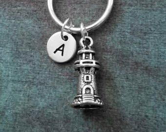 May include: Silver keychain with a lighthouse charm and a silver initial charm with the letter A.