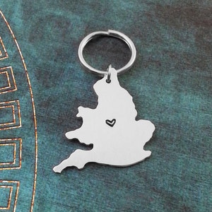 May include: Silver keychain shaped like the outline of England with a small heart in the center.