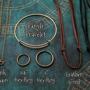 May include: An assortment of jewelry and accessories, including a bangle bracelet, key rings, and chain necklaces. The image also features leather and suede cords. The key rings are 3/4" and 1" in diameter. The text labels the items.