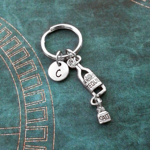 May include: Silver tequila bottle keychain with a salt shaker charm and a letter C charm.
