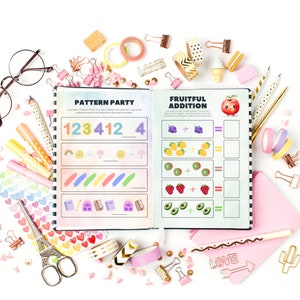May include: An open notebook with colorful pages featuring a "Pattern Party" and "Fruitful Addition" activity. The pages are filled with colorful patterns, numbers, and fruit illustrations. The notebook is surrounded by various colorful school supplies, including pencils, pens, scissors, and washi tape.