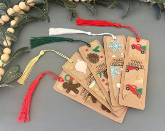 Könnte beinhalten: Eine Sammlung von Lesezeichen zum Thema Weihnachten mit bunten Quasten. Die Lesezeichen zeigen festliche Designs wie Schneeflocken, Lebkuchenmänner und Weihnachtsbäume. Auf jedem Lesezeichen steht "Merry Christmas".