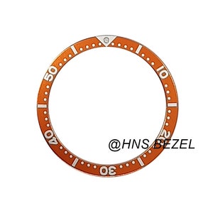 May include: Orange watch bezel with white markings for a dive watch. The bezel has numbers from 10 to 50 in increments of 10. The text "@HNS BEZEL" is visible in the image.
