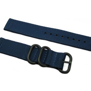 May include: A dark blue nylon watch strap with black hardware and a double keeper loop.