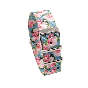 May include: A light blue and pink floral patterned watch strap with a silver buckle. The buckle has the text "HNS" engraved on it.