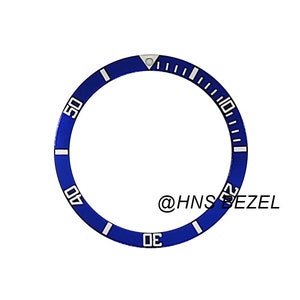 Può includere: Ghiera di orologio blu con segni e numeri bianchi. La ghiera è contrassegnata da numeri da 0 a 60.