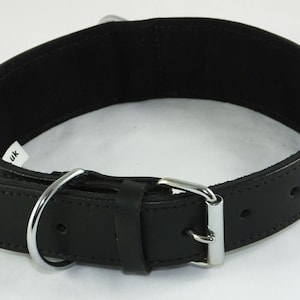May include: Black leather dog collar with a silver buckle and a silver D-ring. The collar has two rows of stitching and a small red label that says "UK".