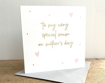 May include: A white card with gold lettering that reads "To my very special mum on mother's day". The card has pink hearts and gold dots scattered across the surface.