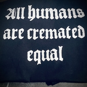 May include: A black t-shirt with white text that reads "All humans are cremated equal."