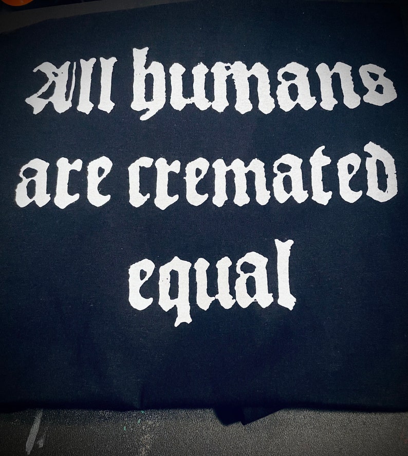 May include: A black t-shirt with white text that reads "All humans are cremated equal."