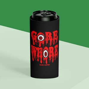 May include: Black can cooler with a red graphic that says "Gore Whore" with dripping blood and eyeballs. The text "Brujas y Vampiros" is at the bottom.