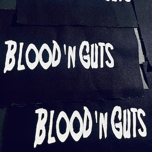 May include: Three black fabric patches with the words "Blood'n Guts" printed in white.