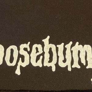 May include: A black fabric patch with the word "Goosebumps" printed in white, stylized in a gothic font.