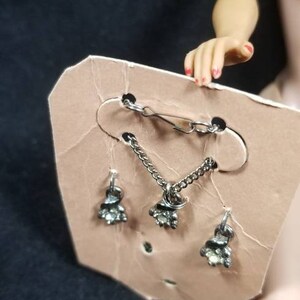 May include: A silver necklace and earrings set with clear rhinestones. The necklace has a clasp and a chain with a small pendant. The earrings are dangle earrings with a small pendant.