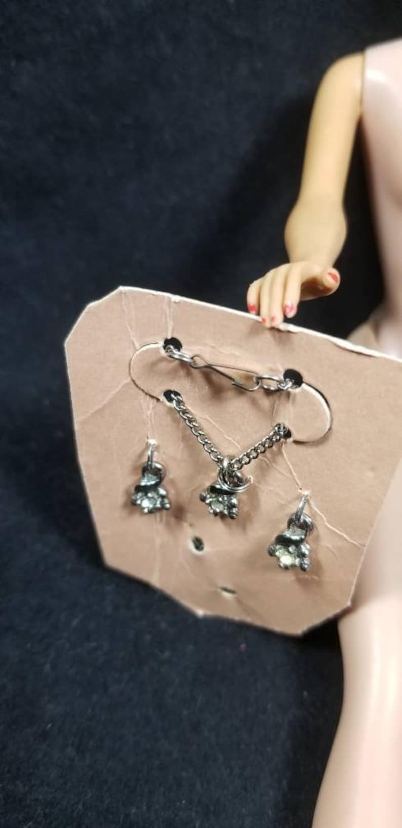 May include: A silver necklace and earrings set with clear rhinestones. The necklace has a clasp and a chain with a small pendant. The earrings are dangle earrings with a small pendant.