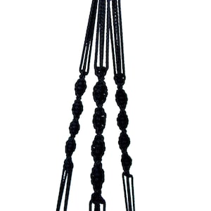 Op de afbeelding: Zwarte macramé plantenhanger met drie strengen en een geknoopt ontwerp.