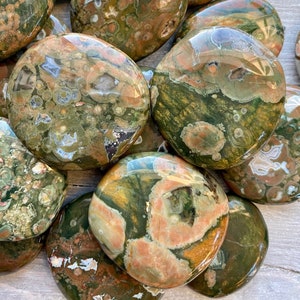 Puede incluir: Una colecci&oacute;n de piedras de jaspe oce&aacute;nico pulidas, cada una con patrones &uacute;nicos de verde, marr&oacute;n y naranja. Las piedras son lisas y tienen un acabado brillante.