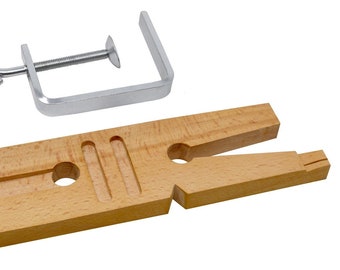May include: A wooden ring mandrel with a metal clamp. The mandrel has a V-shaped opening and two holes for holding rings. The clamp is used to secure the ring in place.