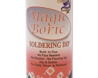 Op de afbeelding: Een witte plastic fles met een rood en wit etiket. Het etiket heeft de tekst "Magic Boric Soldering Dip" en bevat de tekst "Built-In Flux, No Flux Needed, No Alcohol - No Flaming Up, Dip & Solder, For Gold, Silver, & Platinum". De fles is 473 ml.